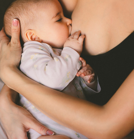Bébé qui tète dans les bras de sa mère