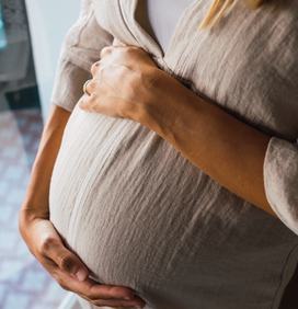 Femme enceinte se tenant le ventre, une main sur le bas du ventre et une main sur le haut du ventre