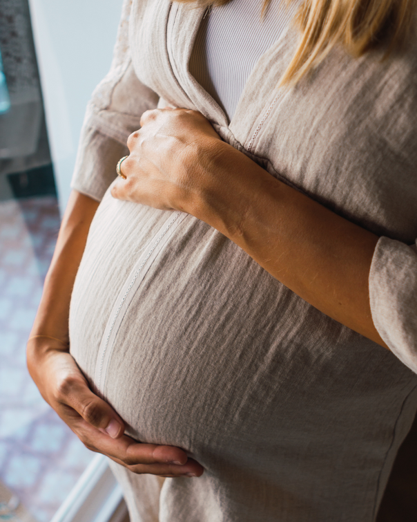 Femme enceinte se tenant le ventre, une main sur le bas du ventre et une main sur le haut du ventre